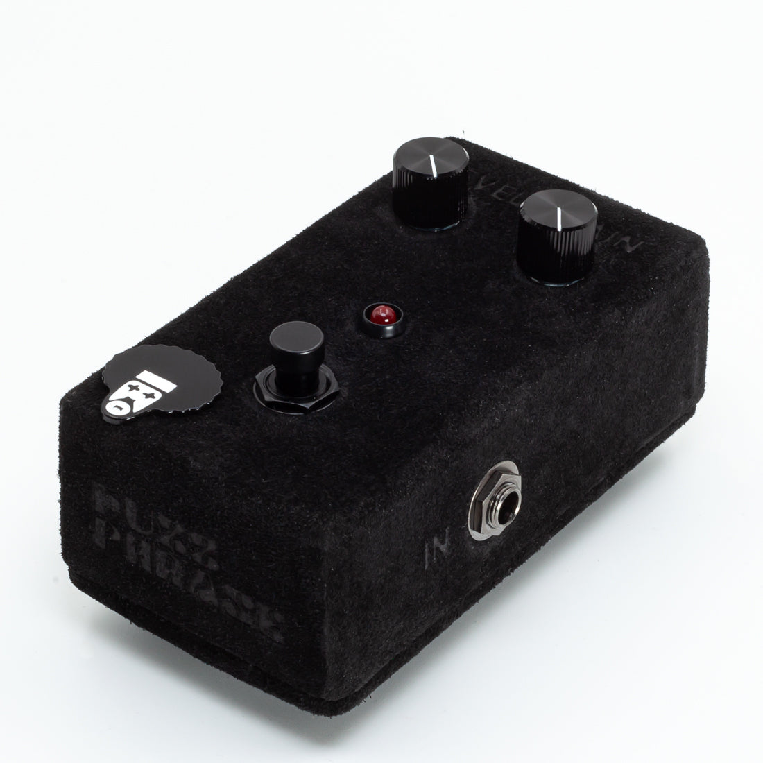 Black guitar effects pedal with knobs and a label on a white background