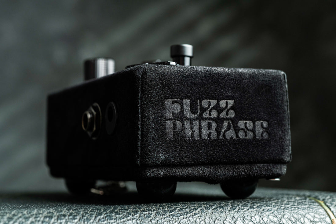 Fuzz Phrase guitar effects pedal on a textured surface with a blurred background