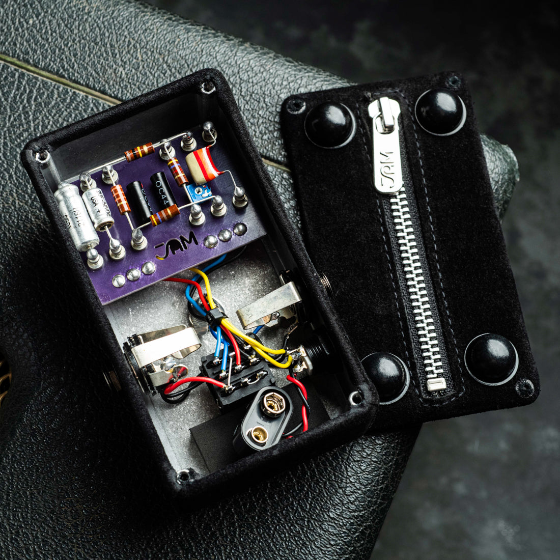 Black suede pedal enclosure with electronic components in the back