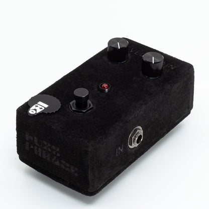 Black guitar effects pedal with knobs and a label on a white background