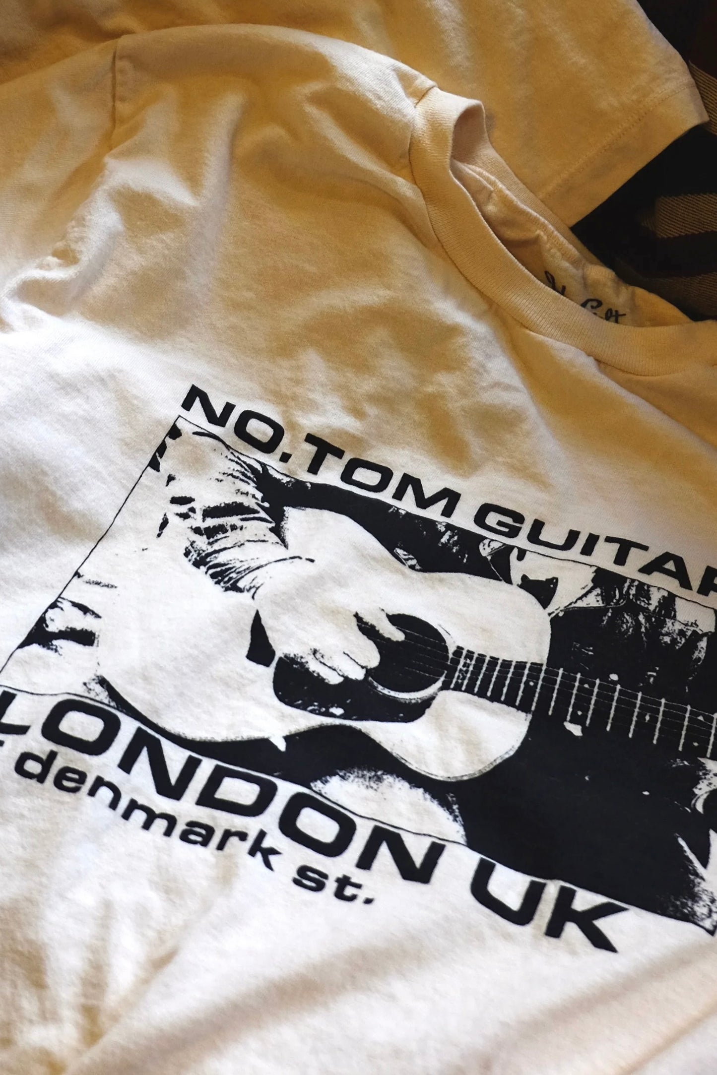 closeup of Limited Edition No.Tom T Shirt in white with black guitar logo